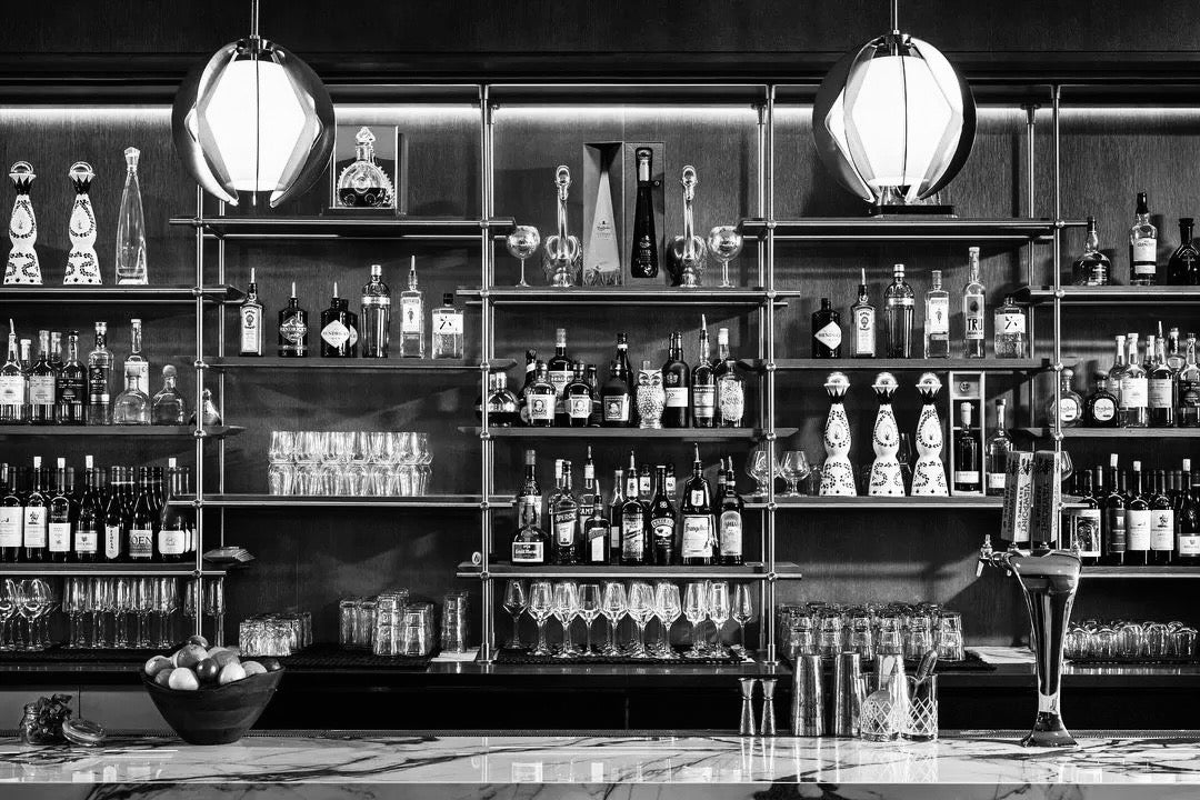 Bar setup with shelves stocked with bottles and glasses, featuring a modern design.