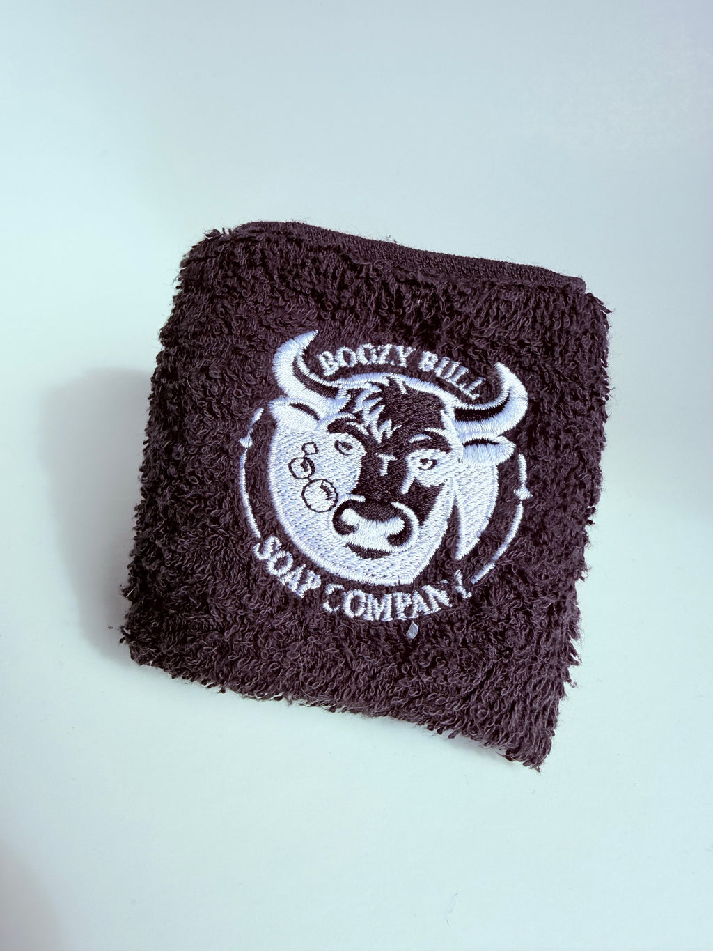 Folded towel with a logo for Boggy Bull Soap Company on a light gray background