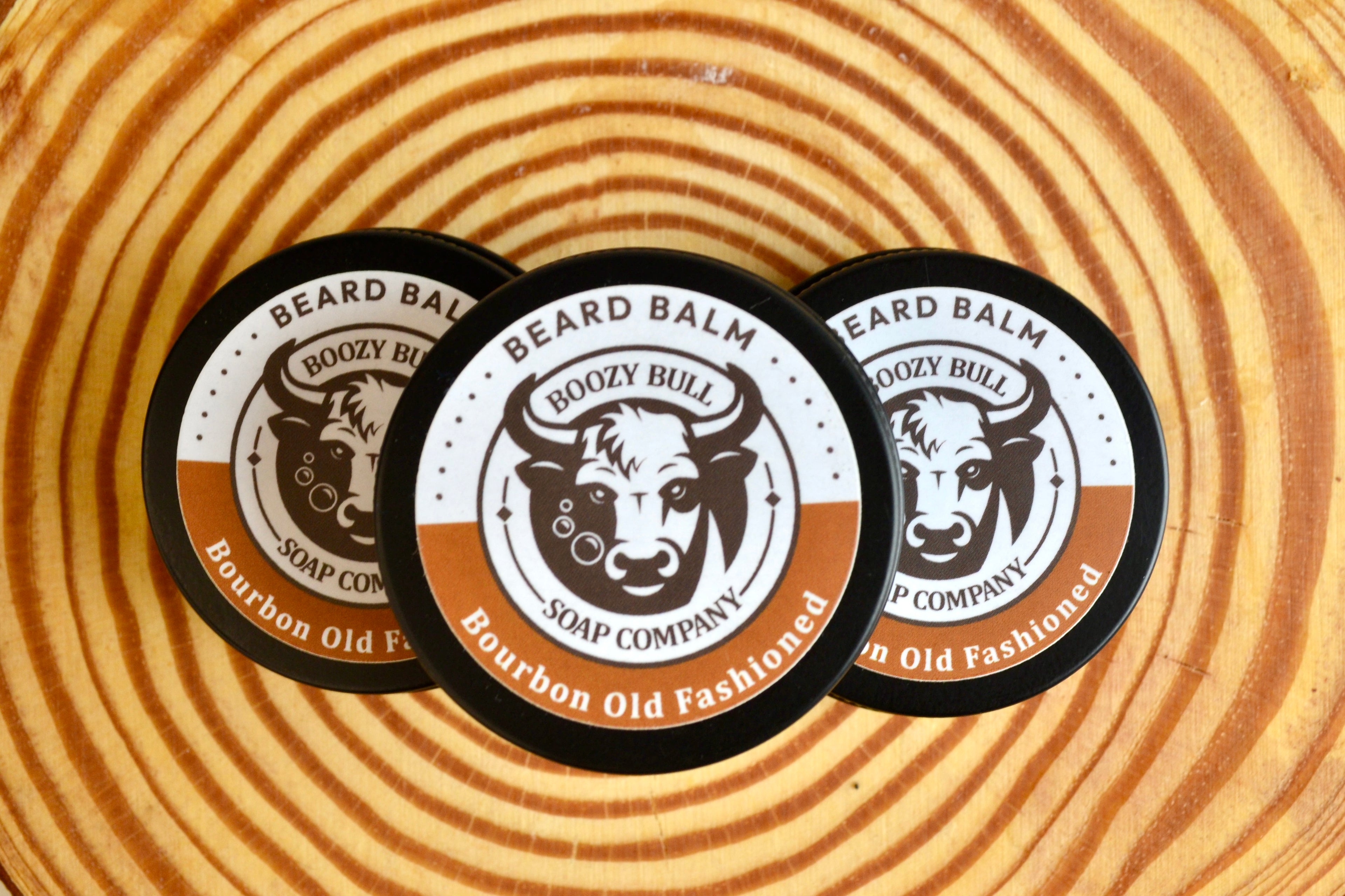 Three containers of Beard Balm on a wooden surface