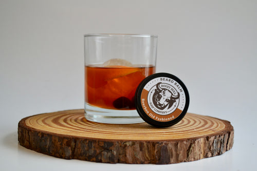 Glass of iced drink with a coaster labeled 'Beard & Black' on a wooden coaster.