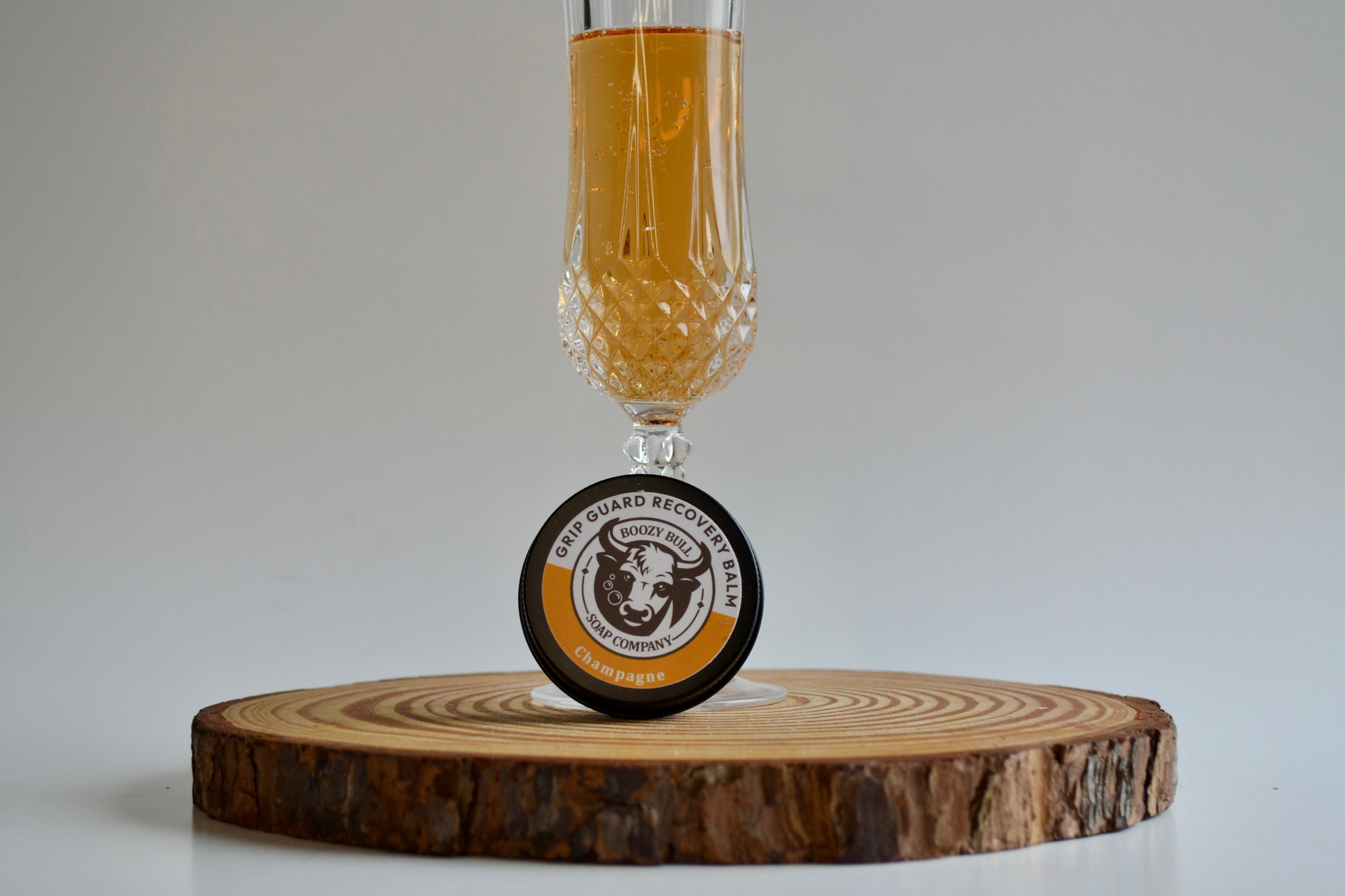 Glass of beer with a wooden coaster featuring a brand logo on a neutral background