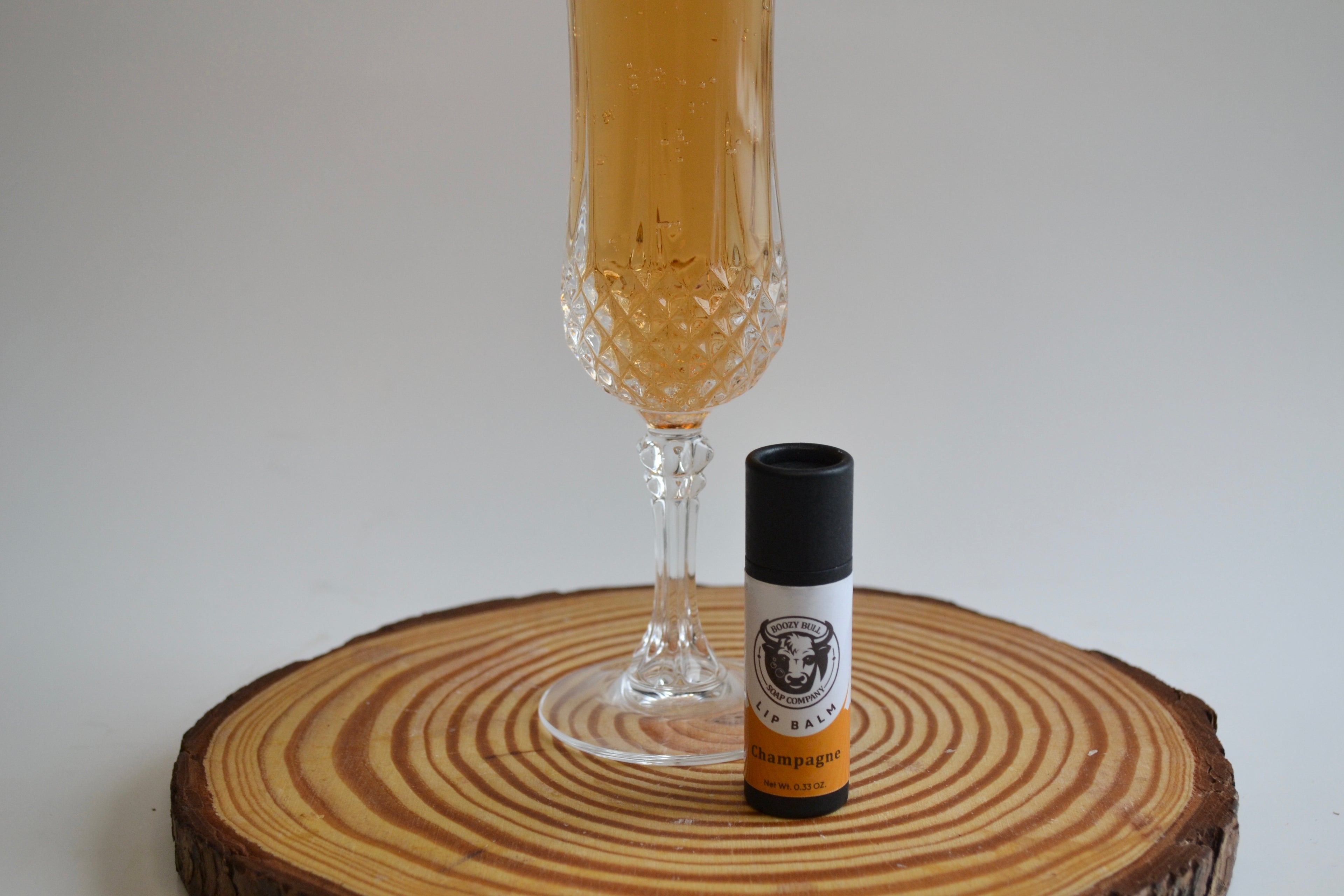Bottle of champagne and a glass on a wooden coaster with a white background