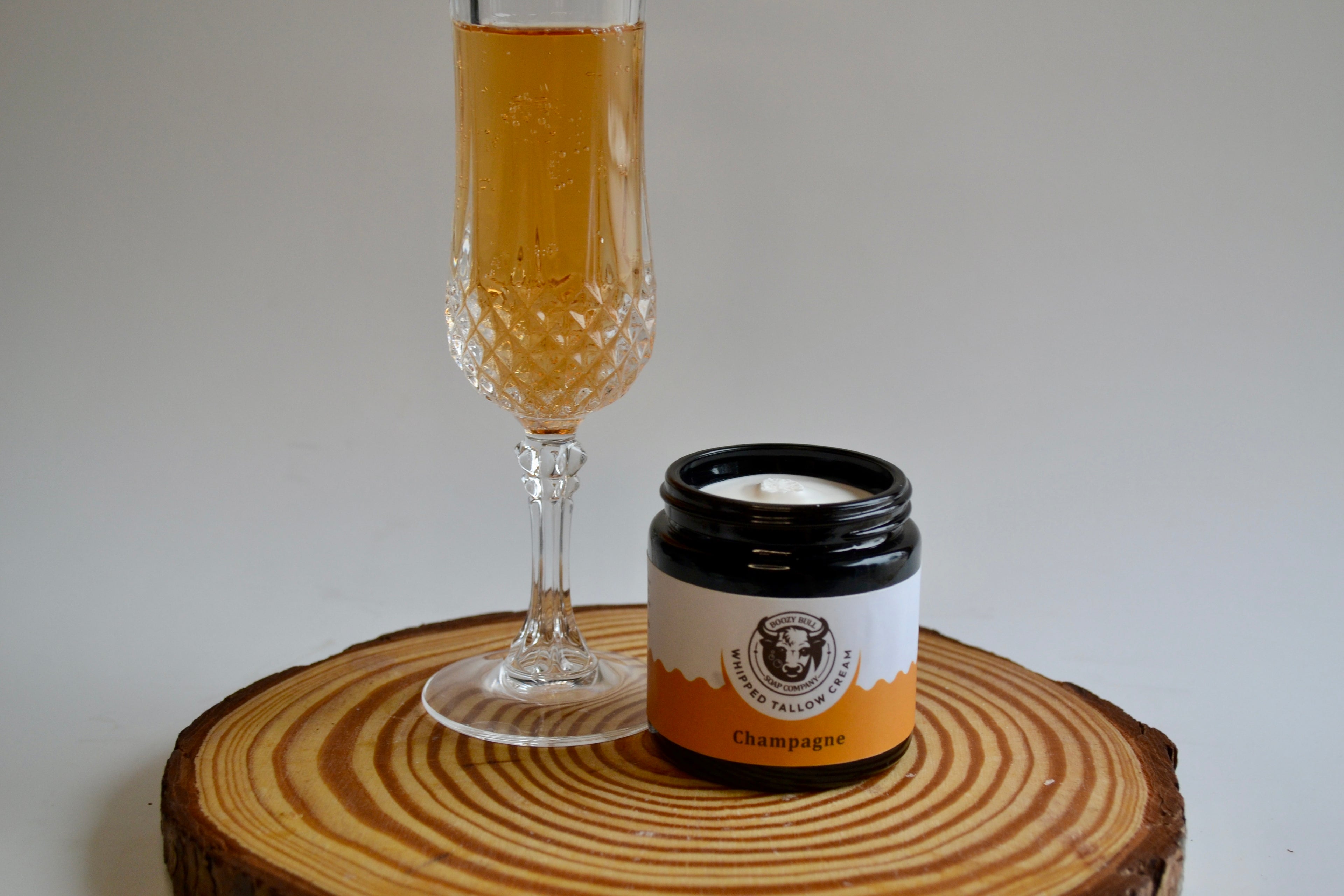 Champagne glass and candle on a wooden coaster with a white background