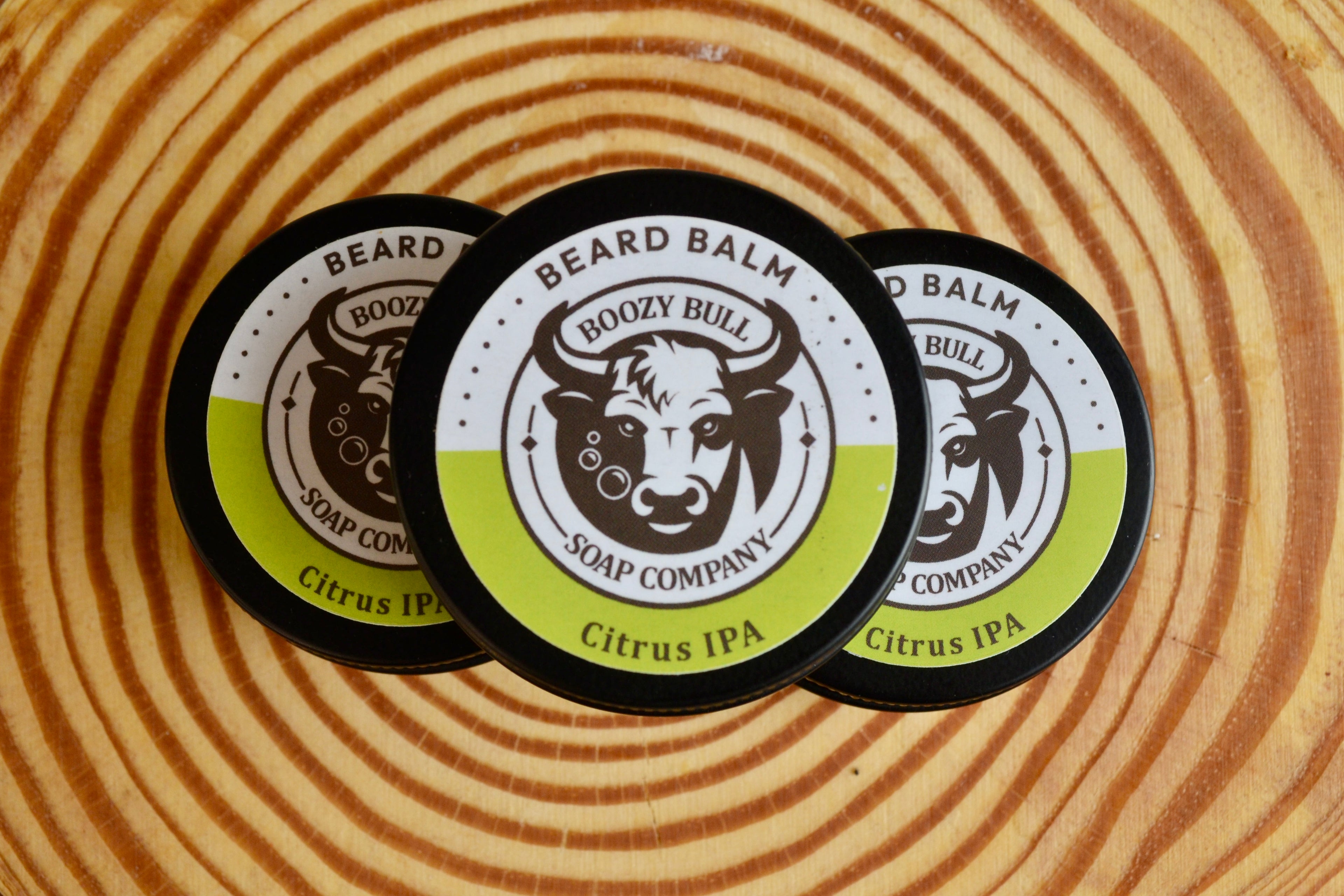 Three boozy bull Beard Balm Containers on a wooden surface