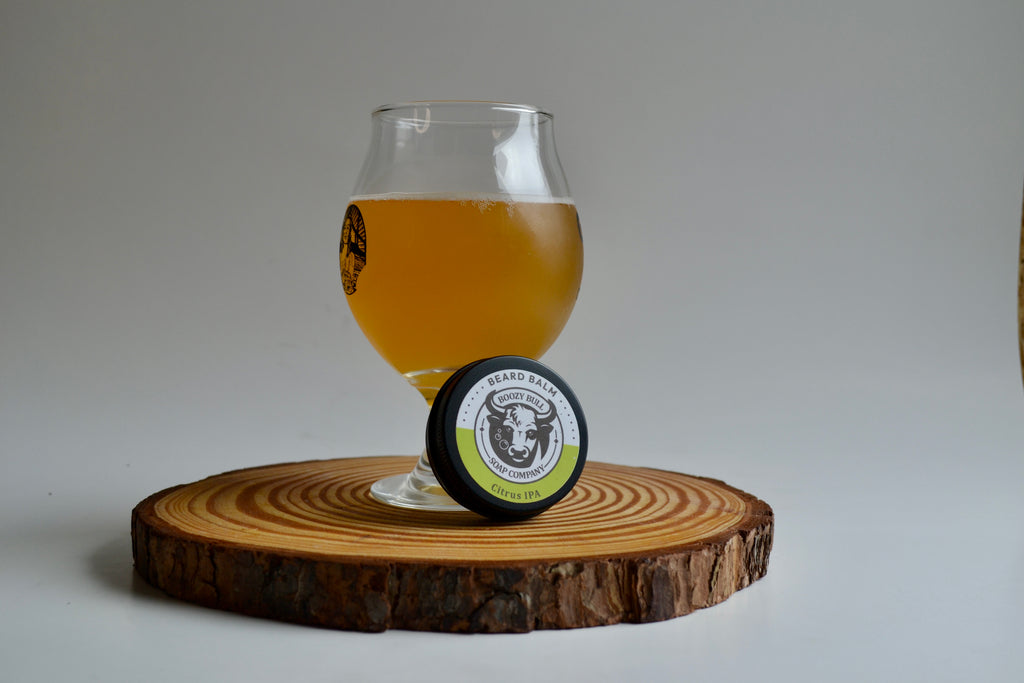 Glass of beer and a circular product on a wooden coaster with a plain background