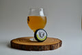 Glass of beer and a circular product on a wooden coaster with a plain background