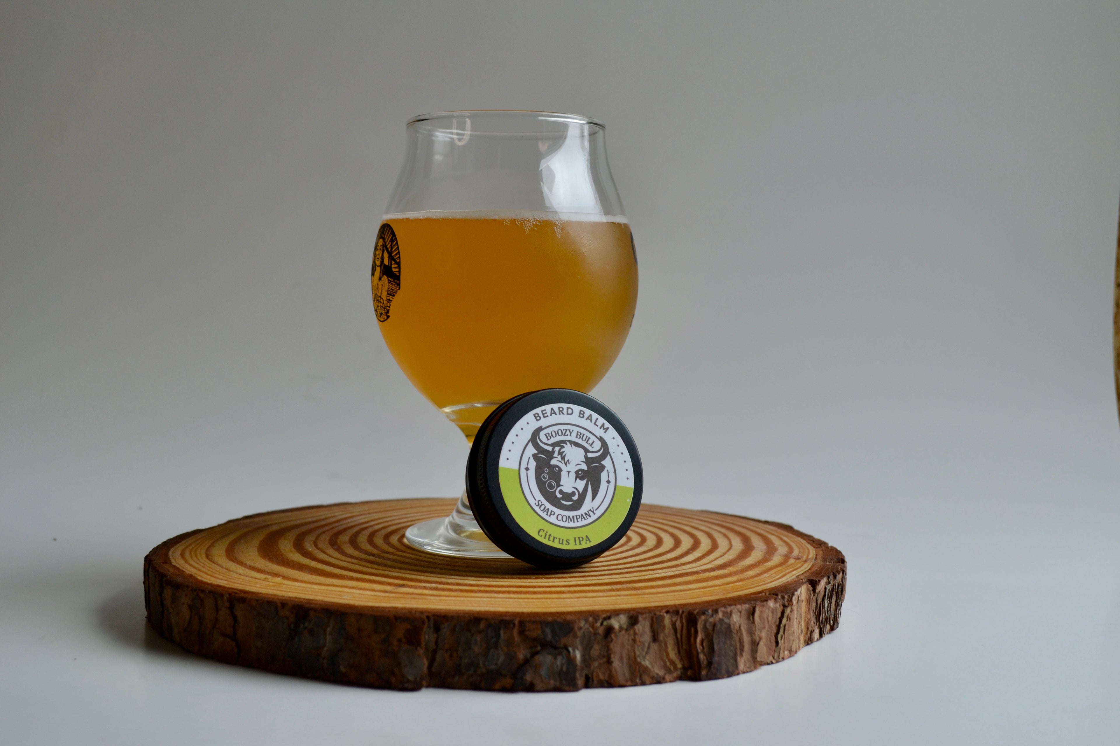 Glass of beer and a circular product on a wooden coaster with a plain background