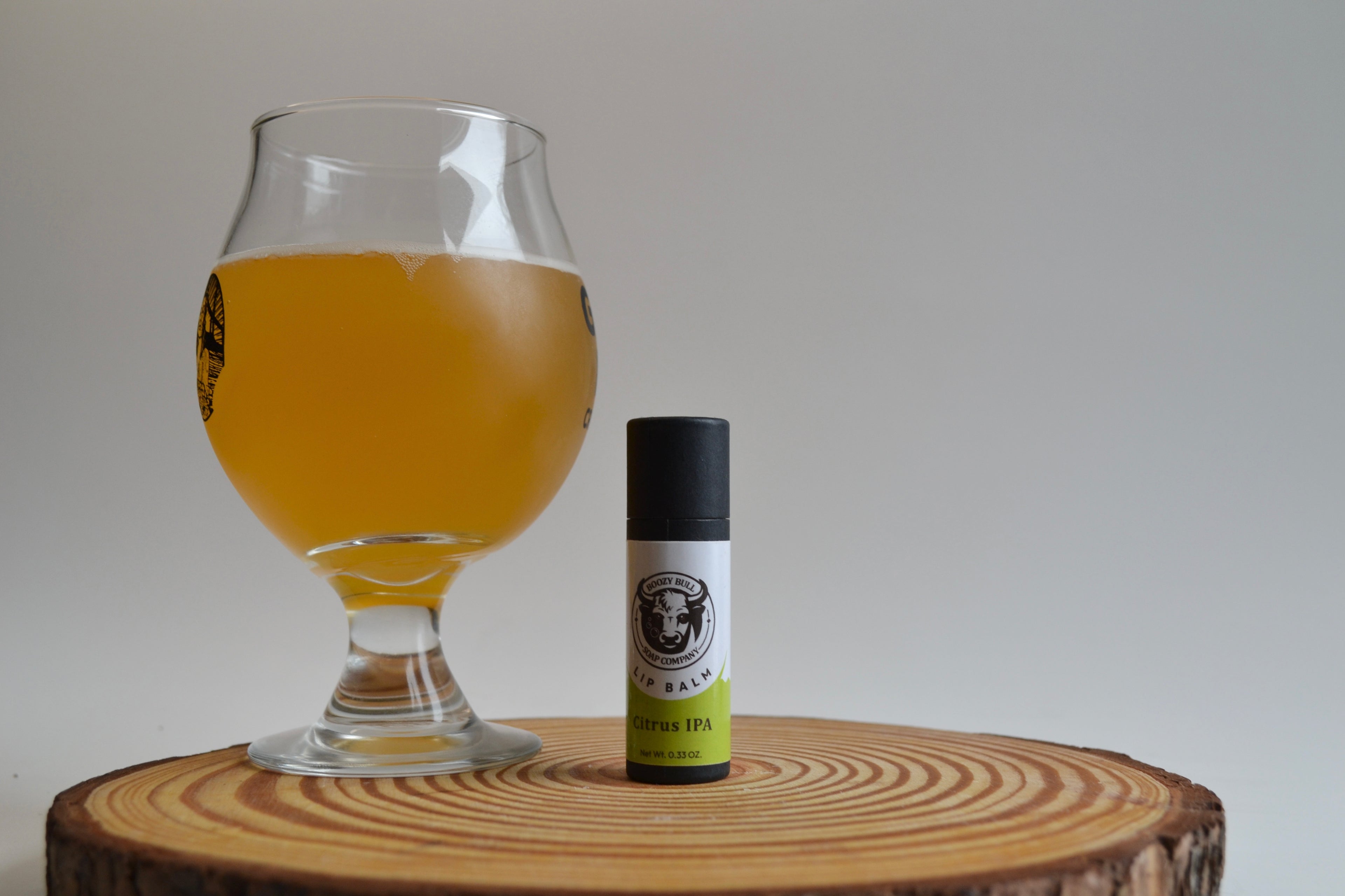 Glass of beer next to a bottle on a wooden surface with a plain background