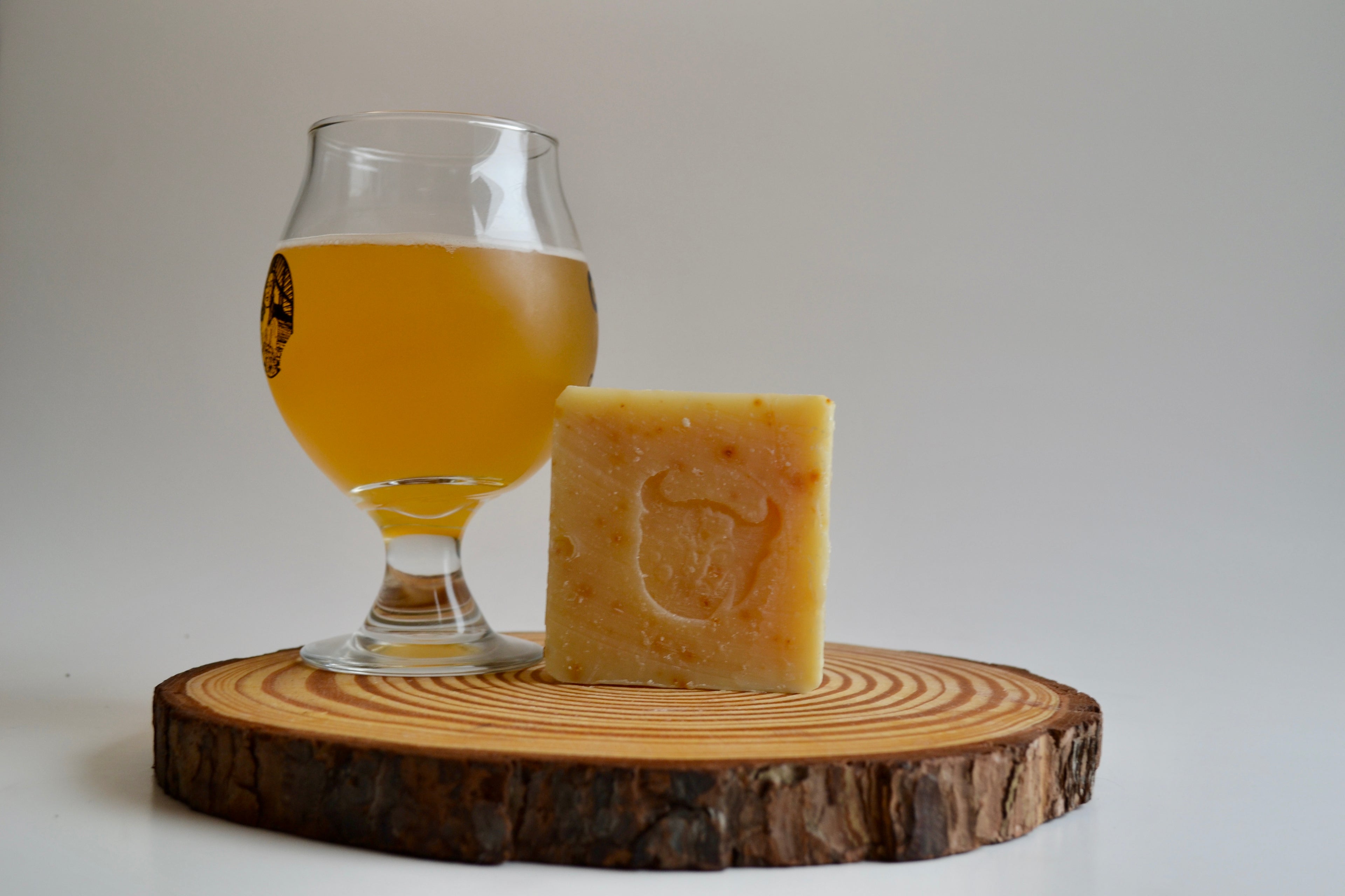 Bar of soap with a logo next to a glass of beer on a wooden coaster