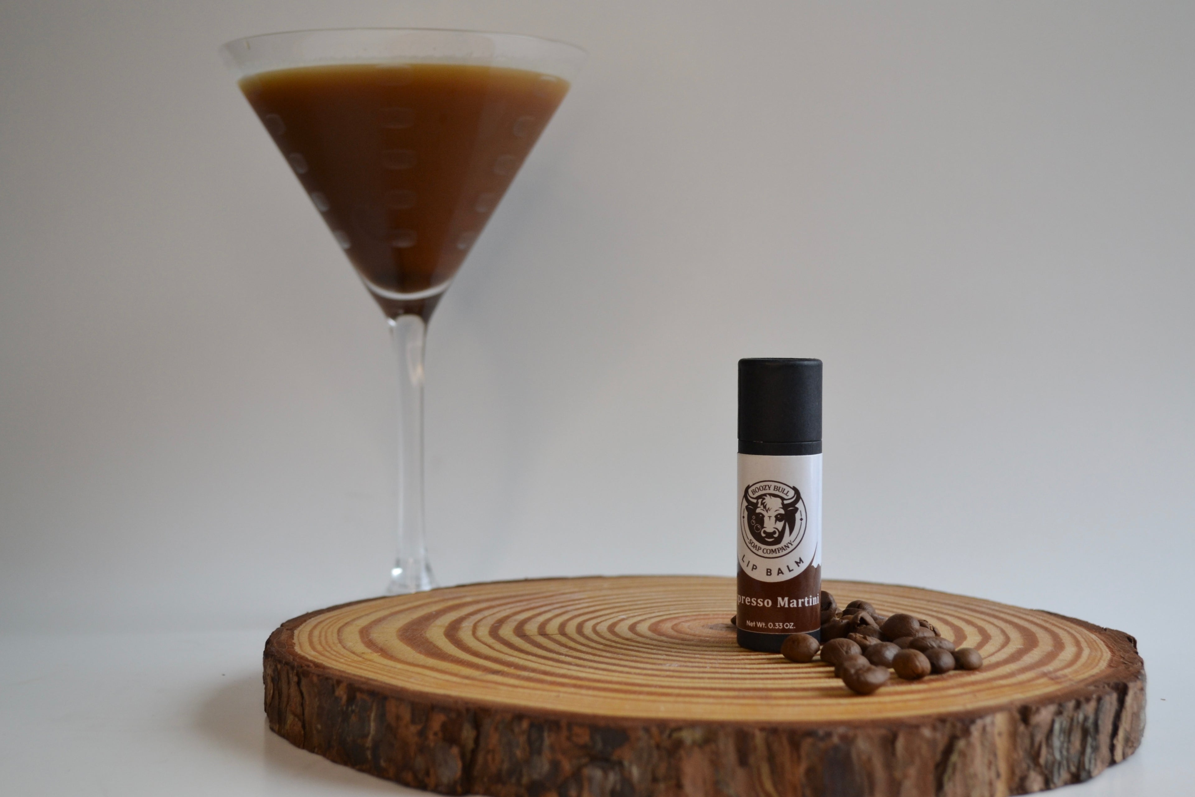 Vial of coffee extract on a wooden board with a martini glass filled with a brown liquid.