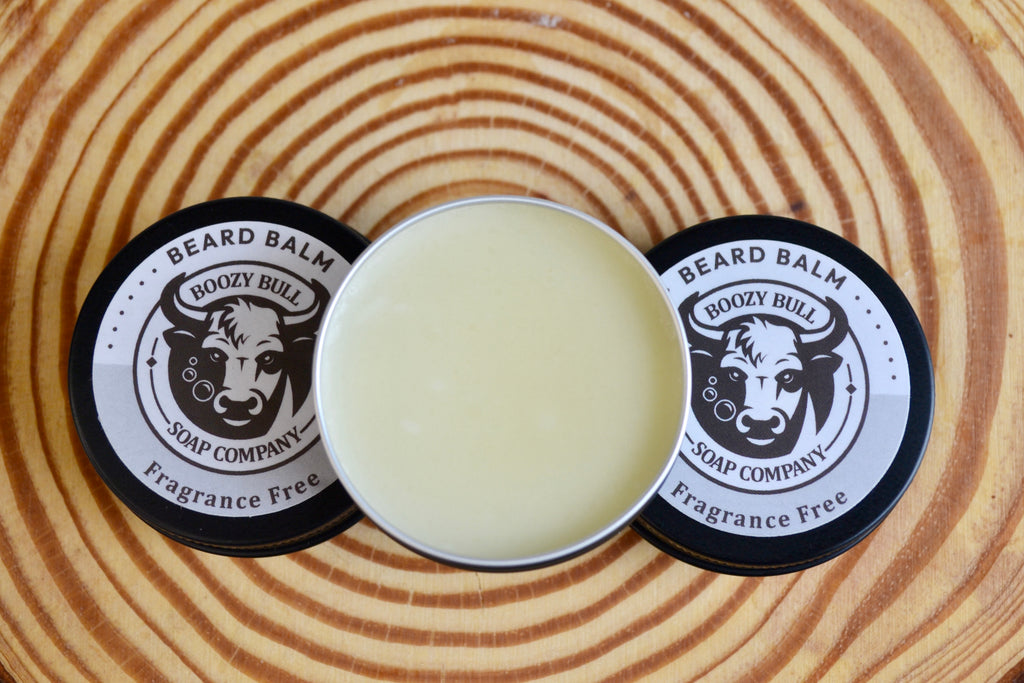 Beard balm container with lid on a wooden surface, featuring 'Boozy Bull Soap Company' branding.