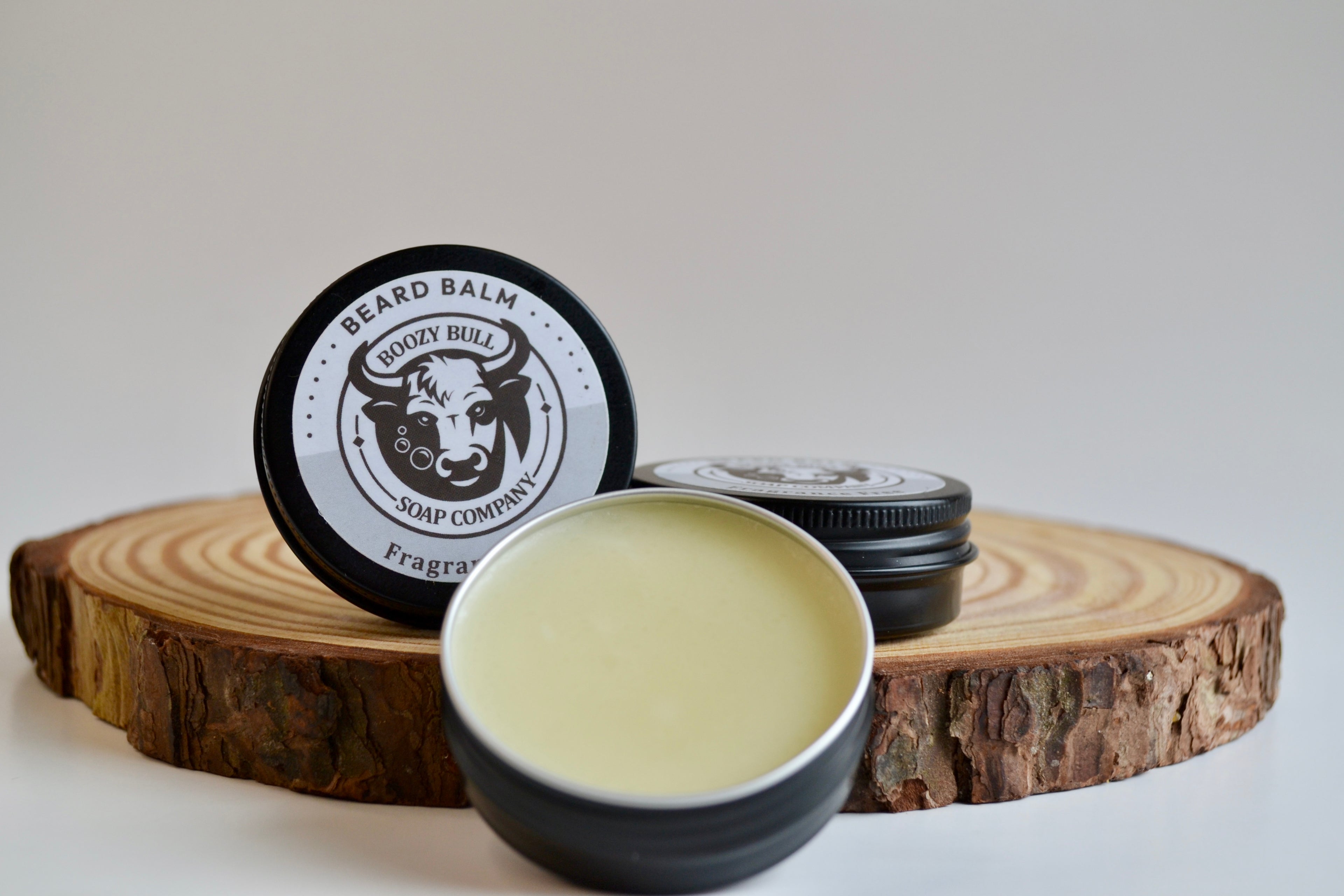 Beard balm container and bowl on a wooden block with a white background