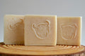 Three bars of soap with embossed designs on a wooden surface