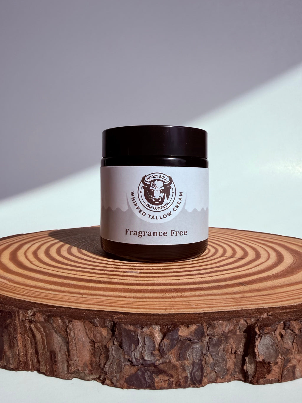 Jar of Whipped Tallow Cream on a wooden surface with a gray background