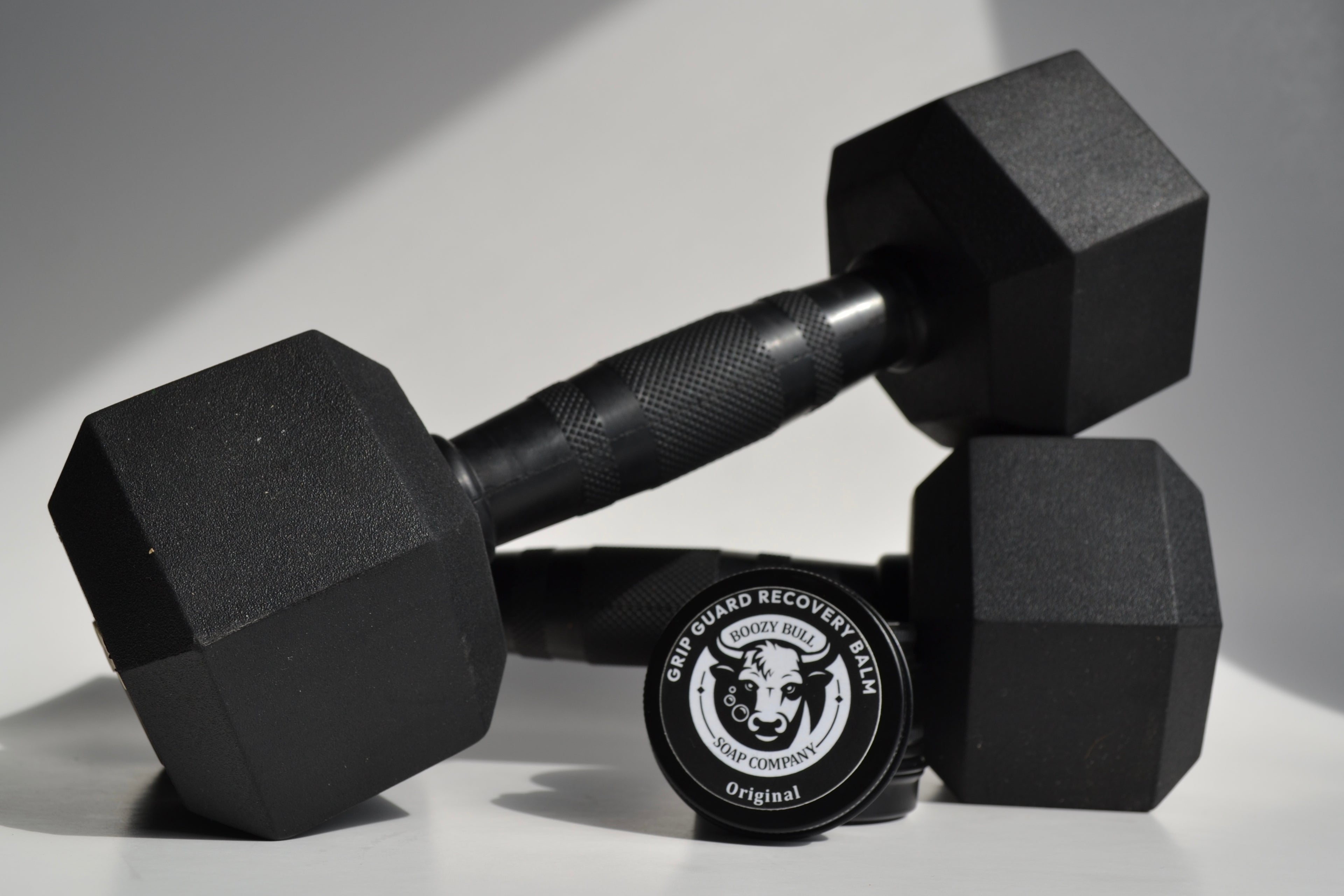 Pair of black hexagonal dumbbells with a weight marker on a light background