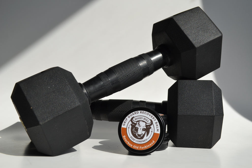 Pair of black hexagonal dumbbells with a weight plate featuring a logo on a light gray background.