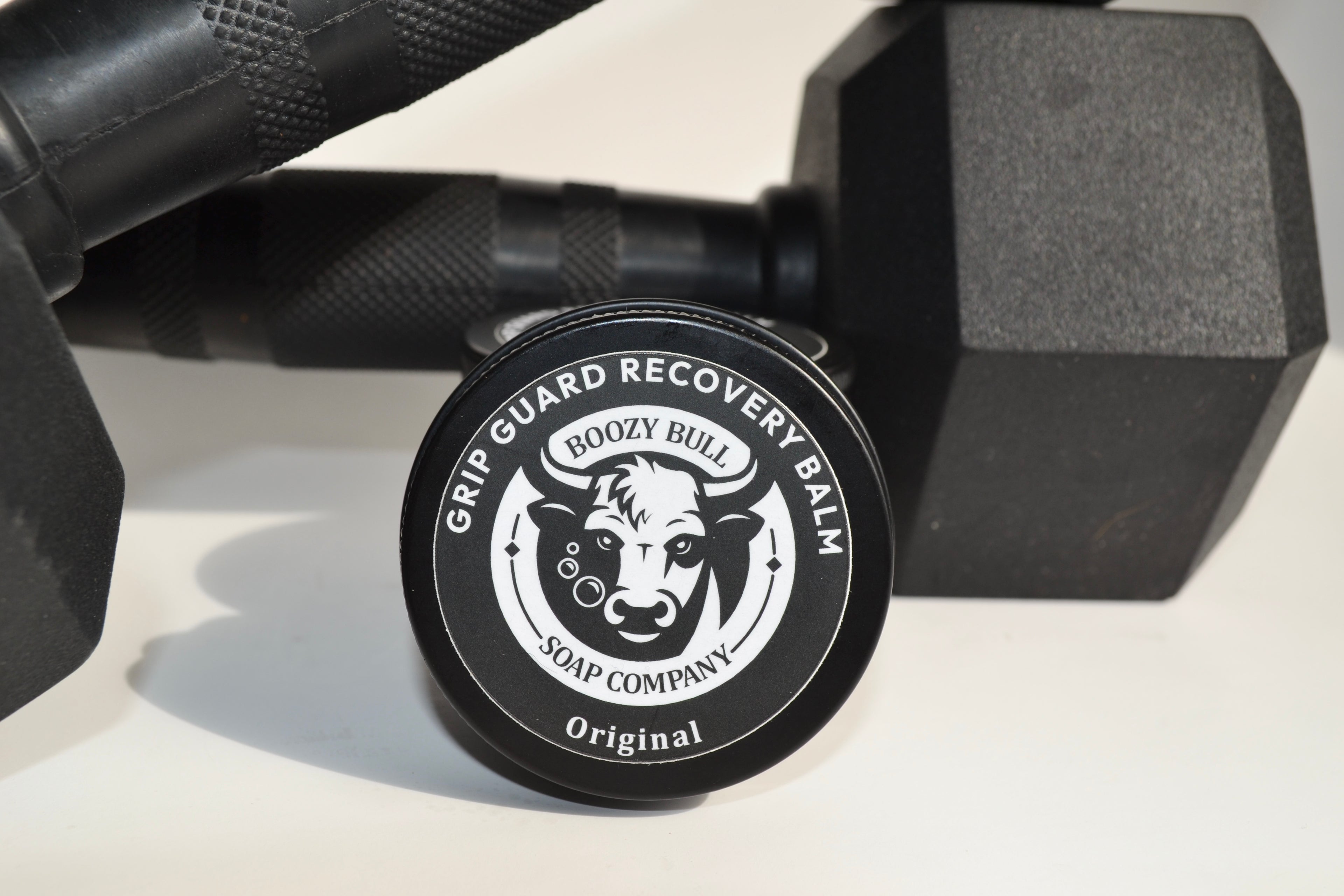Grip Guard Recovery Balm container with 'Boozy Bull Soap Company' logo between two black dumbbells.