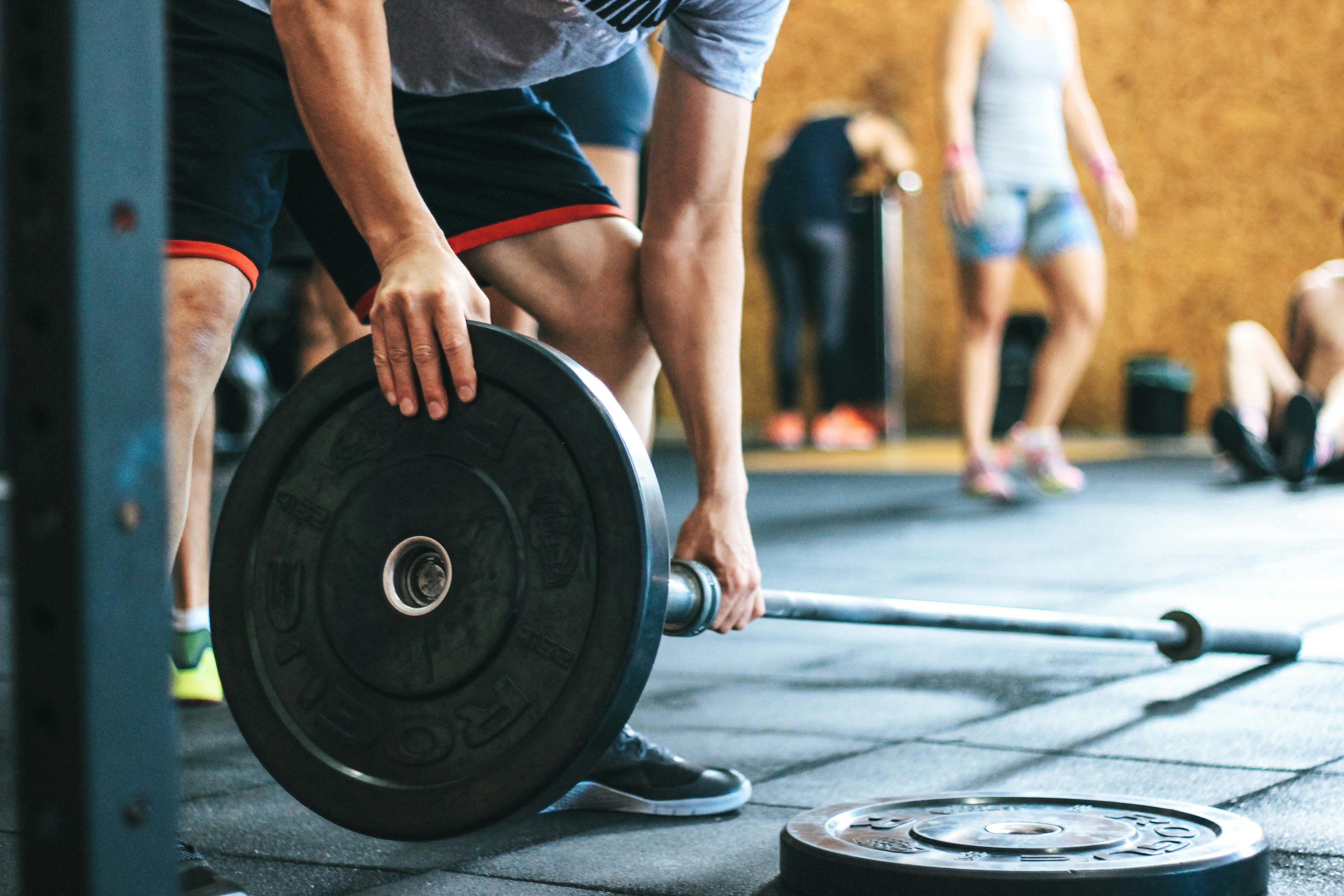 Person lifting a barbell with weights in a gym setting
