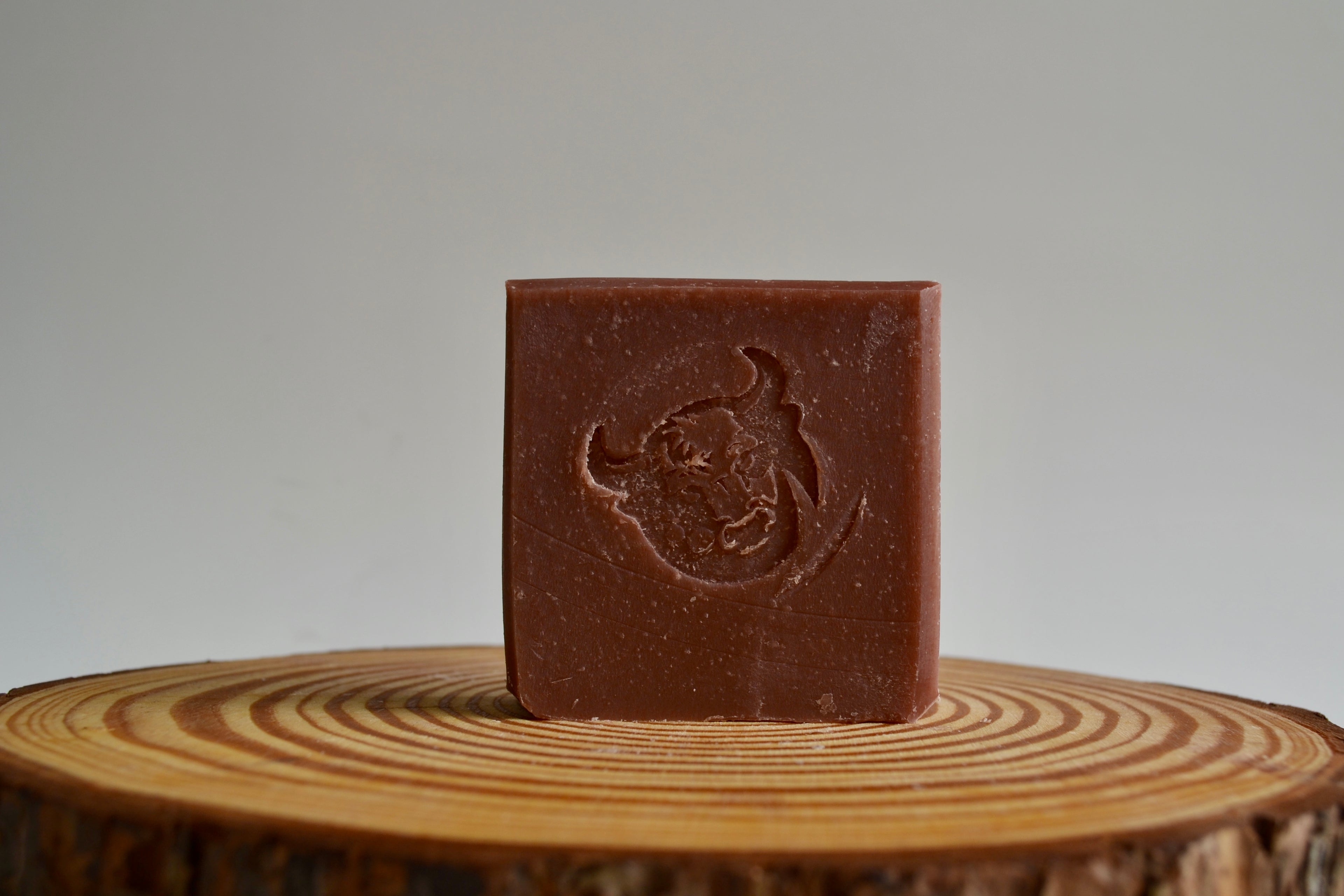 Brown bar of soap with a logo on a wooden surface