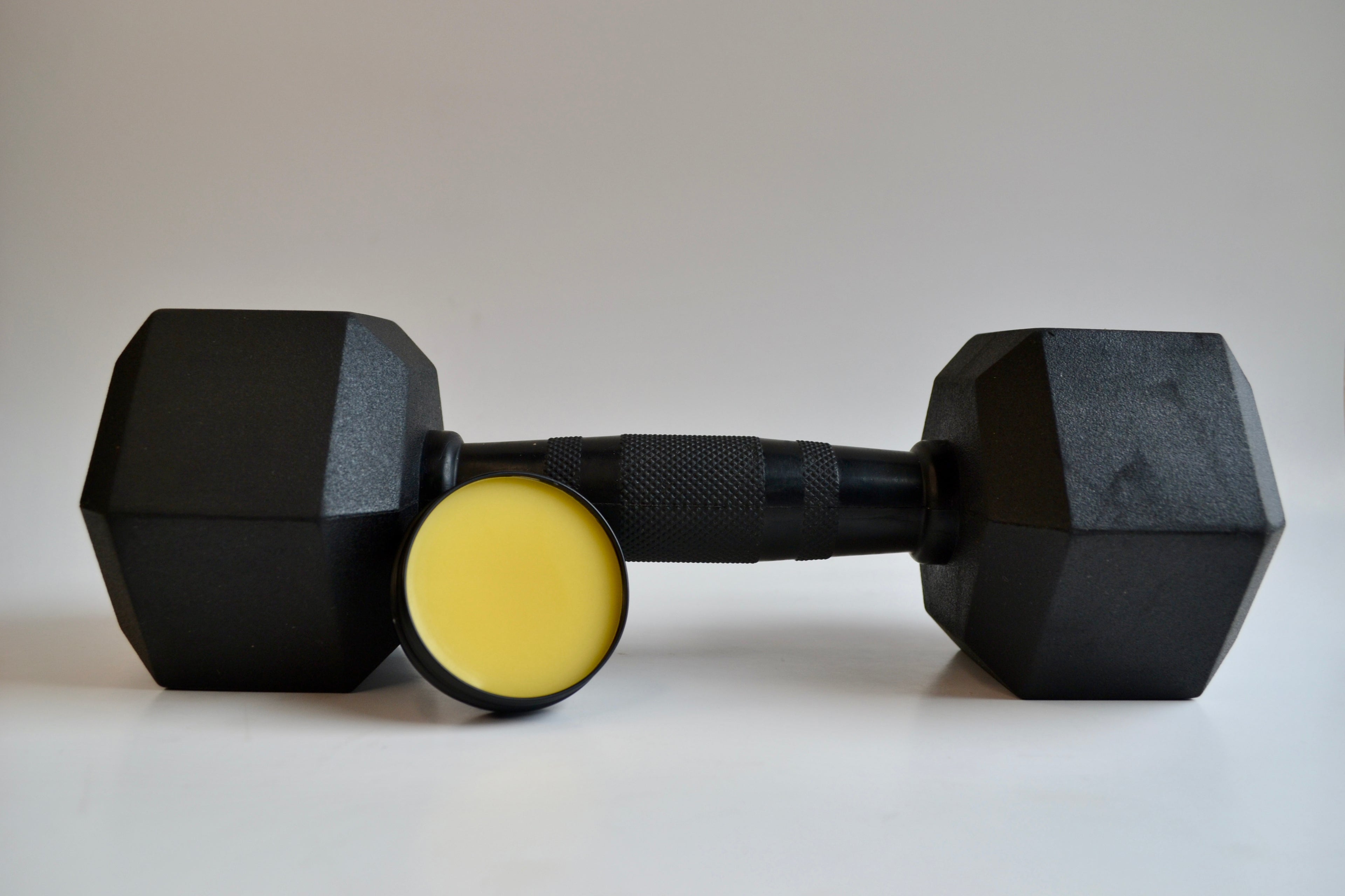 Black hexagonal dumbbells with a yellow grip on a white background