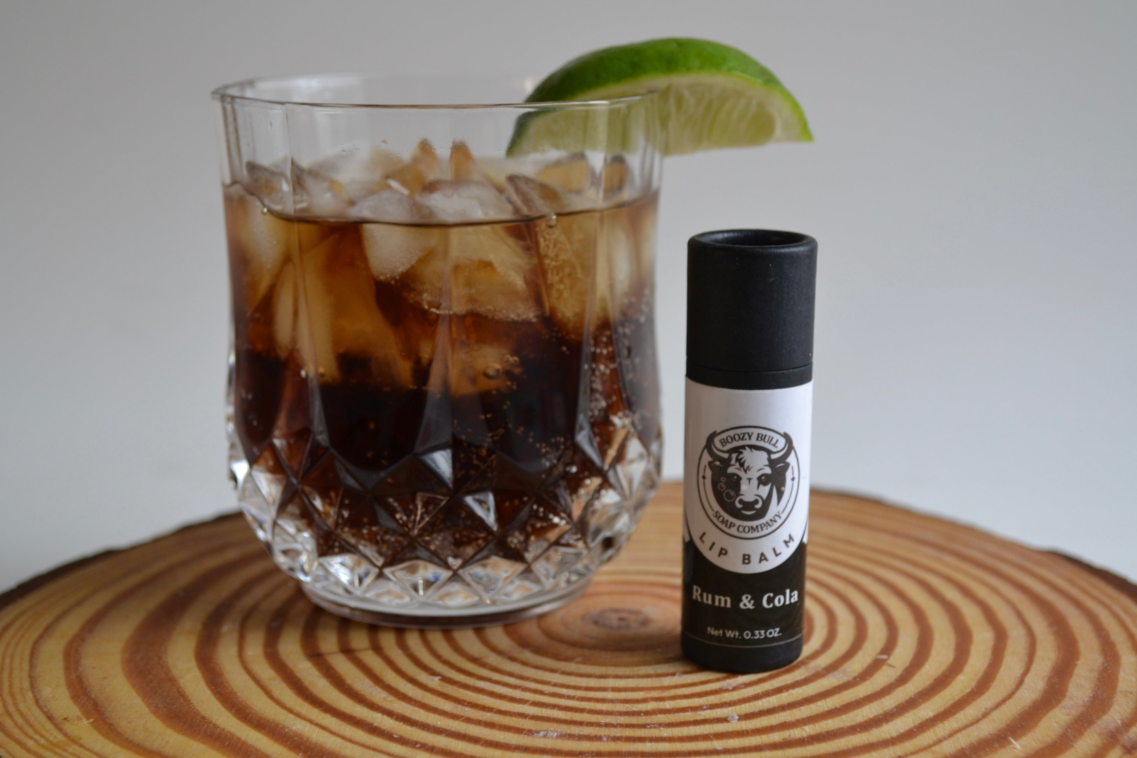 Glass of iced coffee with a lime wedge and a bottle labeled 'Rum & Cane' on a wooden surface.