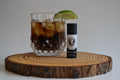 Glass of iced coffee with a lime wedge on a wooden coaster, accompanied by a bottle of Brem & Co's.
