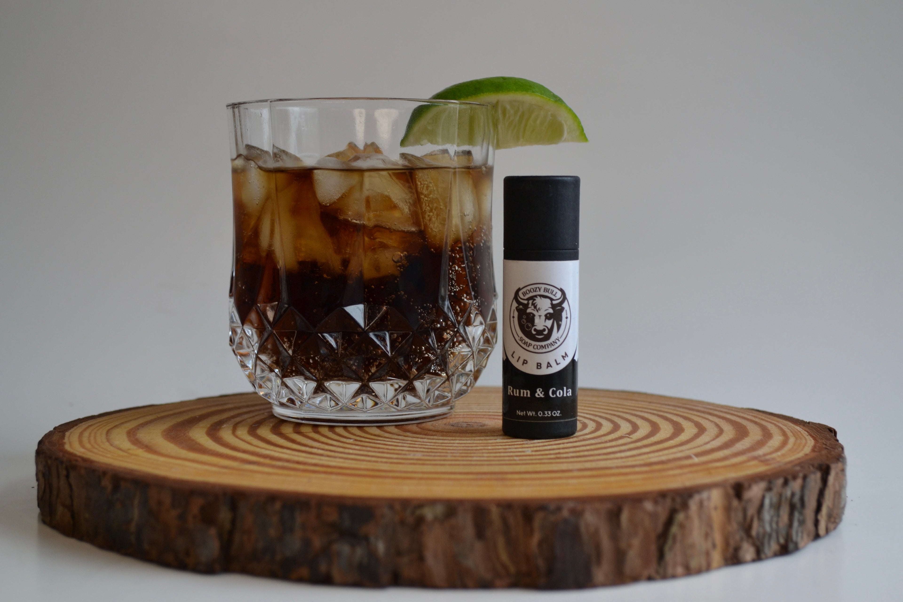 Glass of iced coffee with a lime wedge on a wooden coaster, accompanied by a bottle of Brem & Co's.