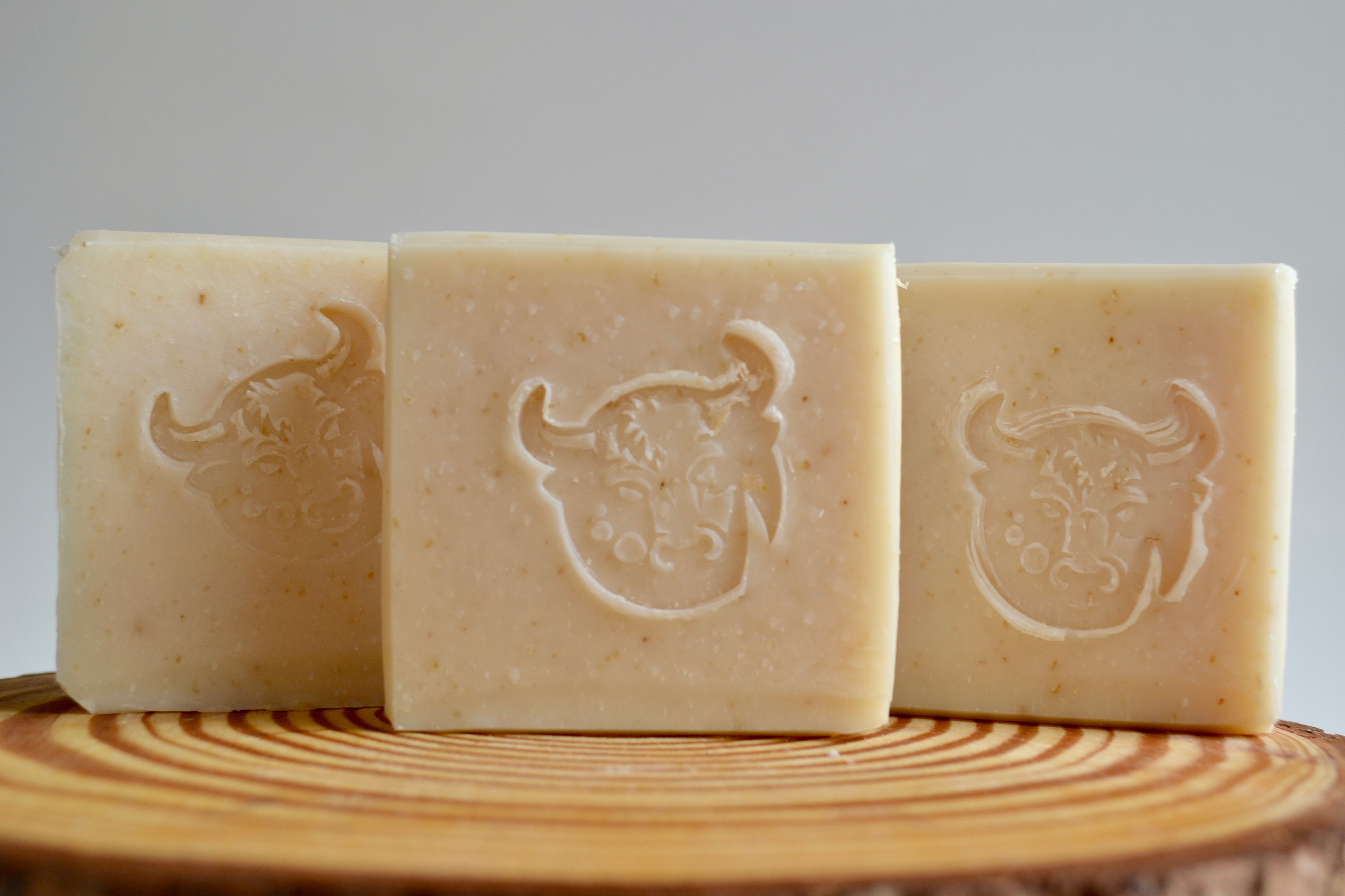 Three bars of soap with embossed designs on a wooden surface